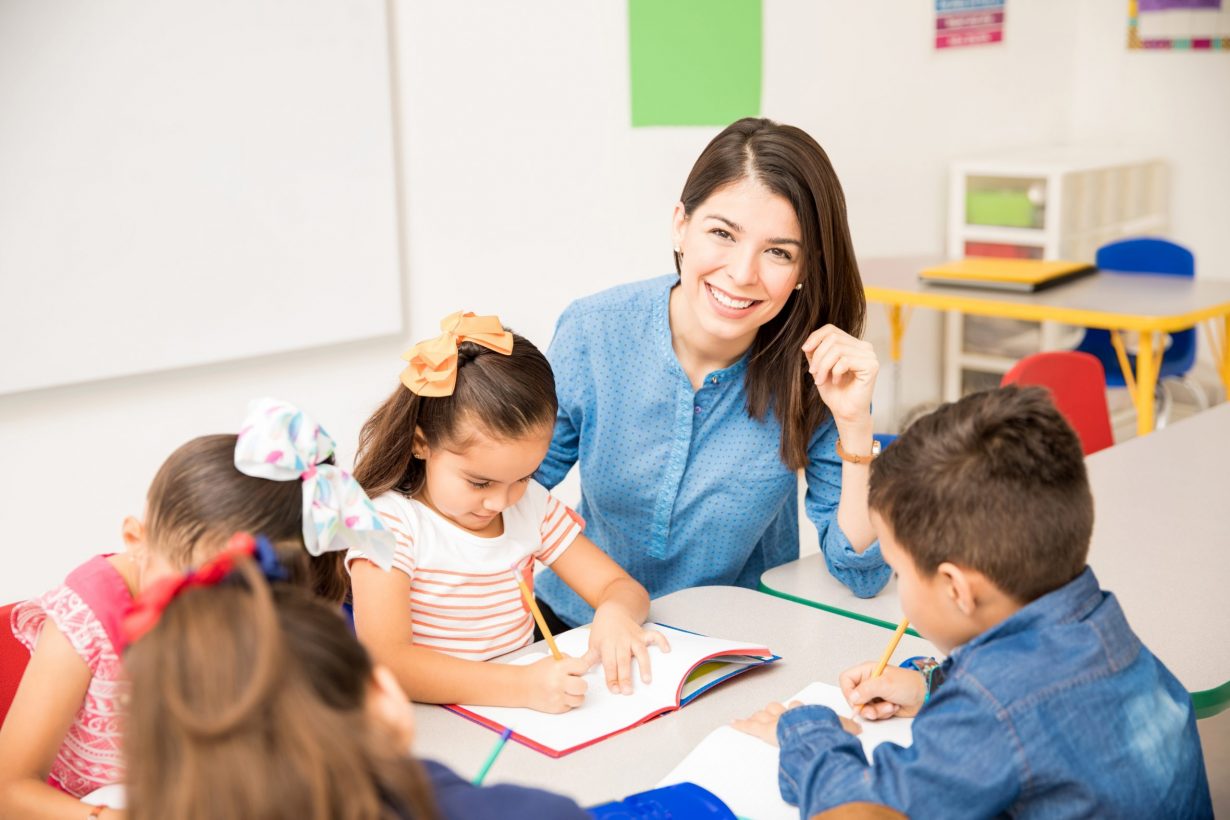 Portrait of a gorgeous Hispanic preschool teacher teaching her students in a classroom